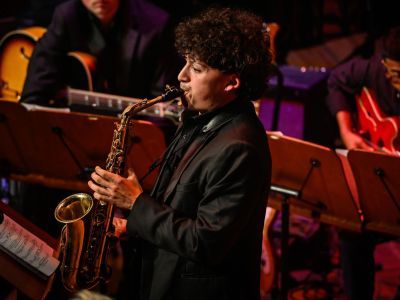 Student playing the saxophone on stage as part of the Jazz ensembles concert